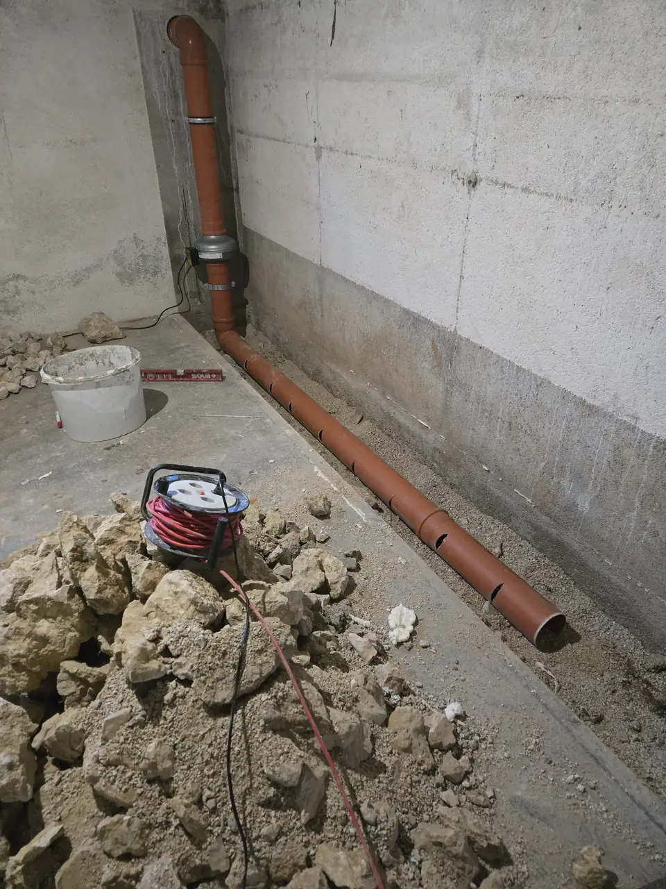 Conduite sous une dalle pendant une intervention radon.