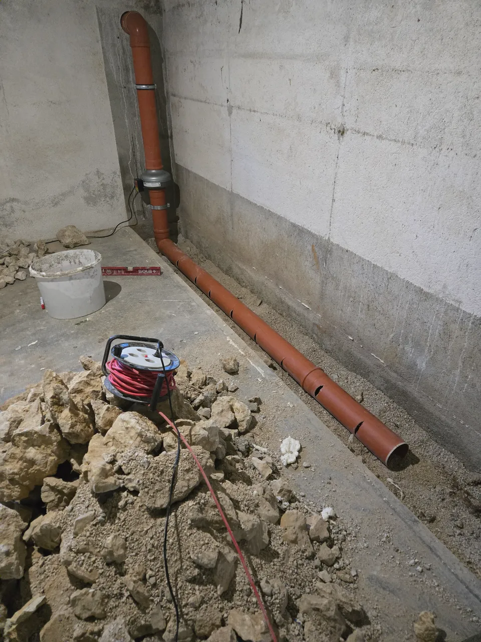 Conduite sous une dalle pendant une intervention radon.