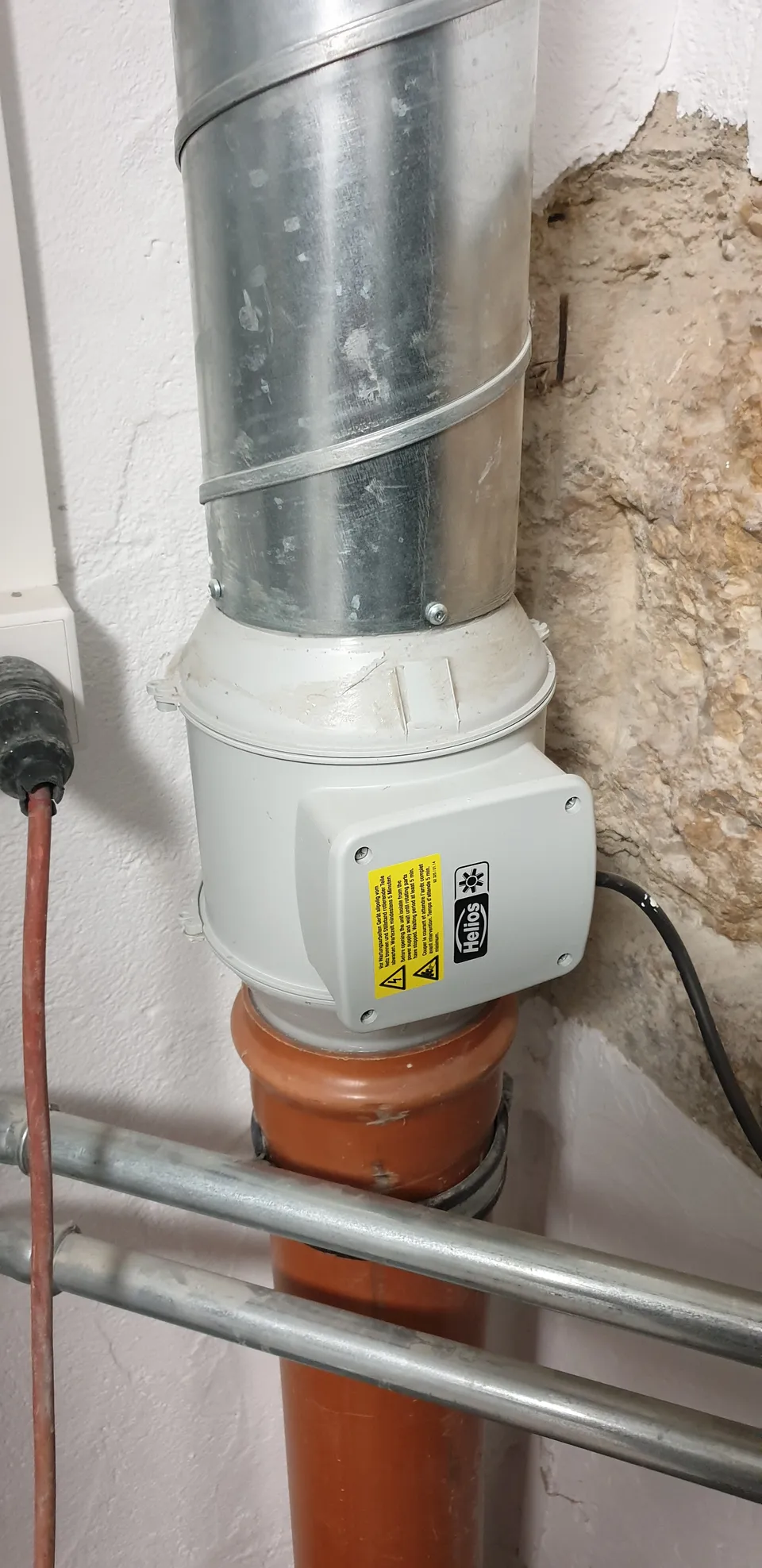 Extracteur installé sur une conduite dans un local technique.